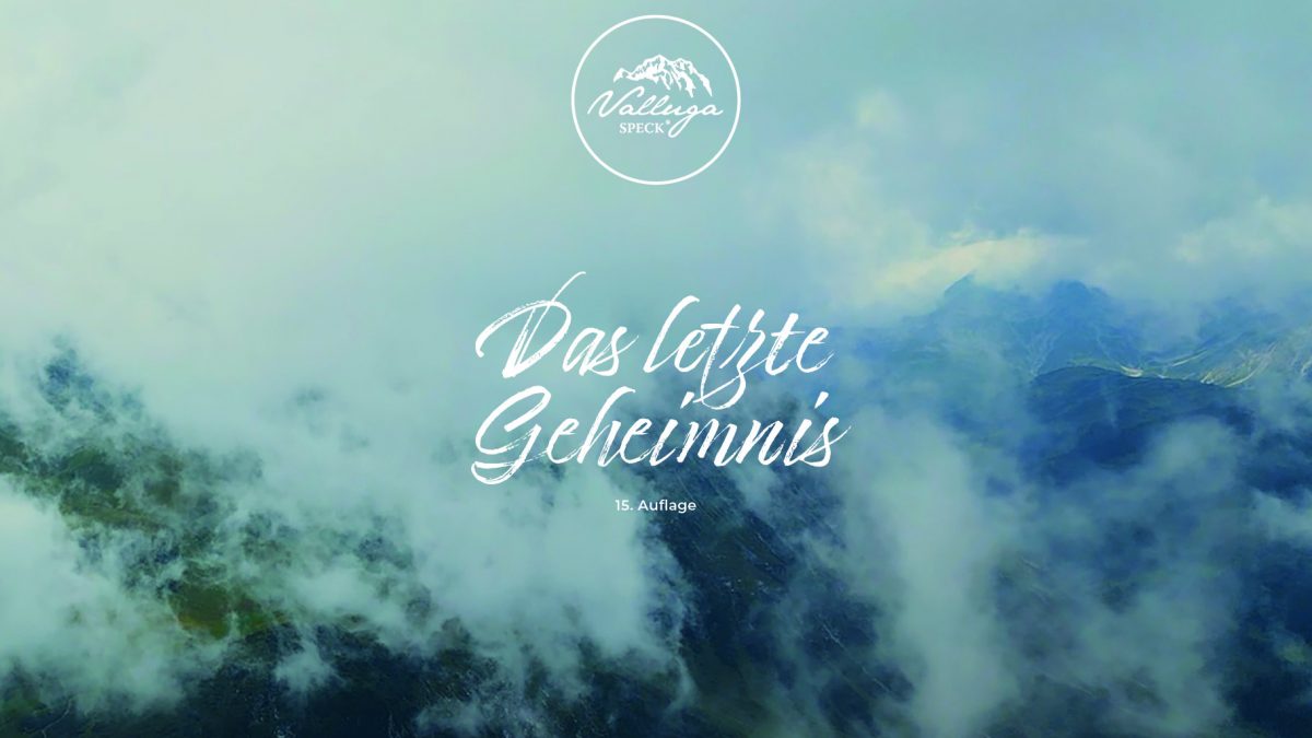 Berggipfel im Nebel im Hintergrund. Darauf das Valluga-Speck-Signet, der Titel "Das letzte Geheimnis" und der Hinweis, dass es sich um die 15. Auflage handelt.