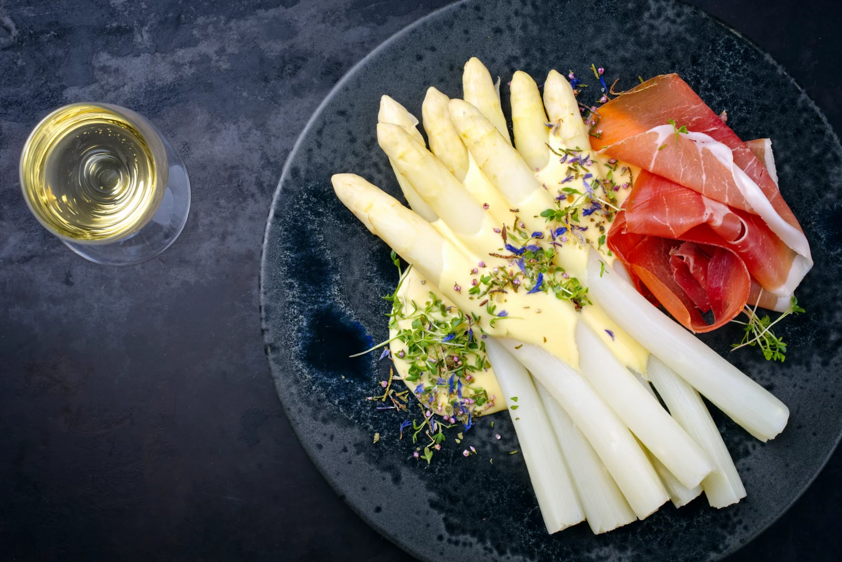 Teller mit Spargel und Schinken, ein Glas Weißwein