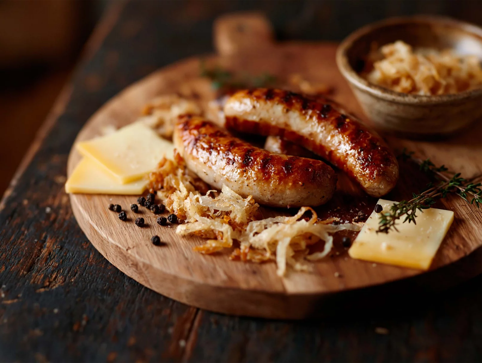 Bratwurst mit Käse und gerösteten Zwiebeln auf Holzbrett